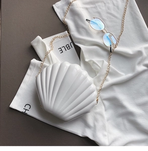 Detail of white shell acrylic crossbody bag with wave texture and gold chain strap