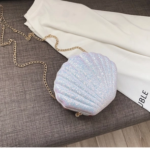 Detail of shell-shaped crossbody bag featuring glitter finish and gold chain strap