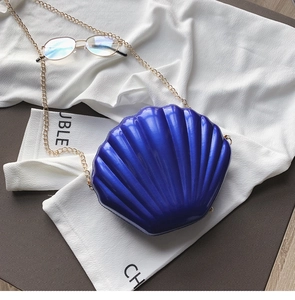 Macro shot of bright blue shell-shaped crossbody bag with radial texture and gold chain