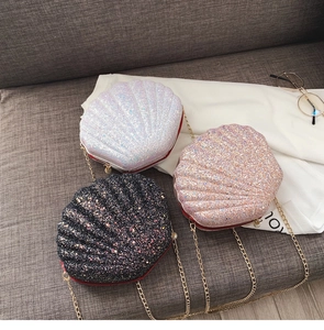 Close-up of three glitter shell-shaped crossbody bags in white, pink, and black