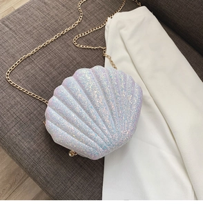 Detailed view of sparkly sequin shell-shaped bag with gold chain and pearl buckle