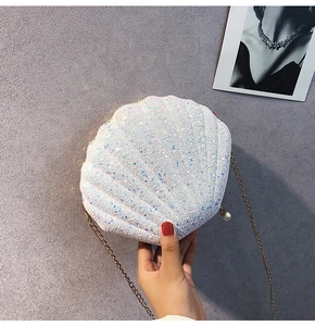 Close-up of shell-shaped crossbody bag with white iridescent sequins and pearl clasp