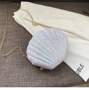 Detail of shell-shaped crossbody bag with iridescent sequins, pearl buckle and gold chain