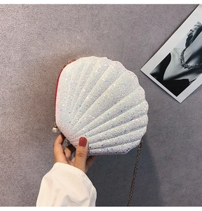 Close-up of shell-shaped white sequin clutch bag with large pearl zipper and chain strap