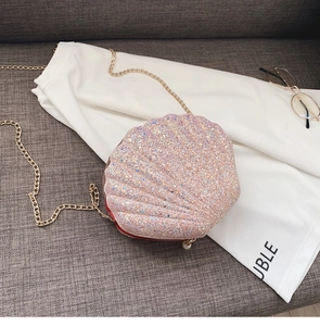 Detail of pink sequin shell bag with golden chain strap and a white pearl charm
