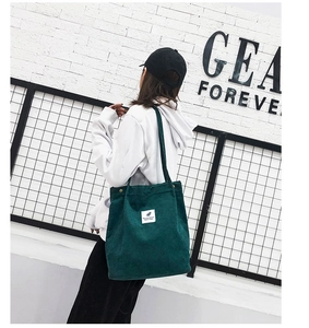 Détail d'un sac cabas en velours côtelé vert foncé avec écusson et bouton-pression