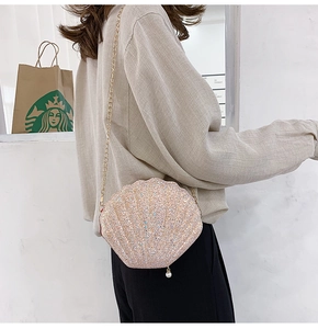 Detail of shell-shaped crossbody bag featuring shimmering sequins and a pearl charm