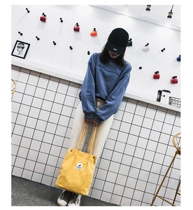 Gros plan détaillé du sac fourre-tout en velours côtelé jaune avec étiquette blanche