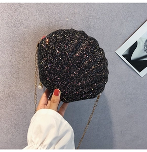 Detail of black sequin shell bag with golden chain strap and pearl charm accent