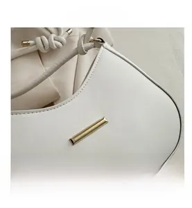 Macro shot of white leather shoulder bag featuring a sleek gold metal bar detail
