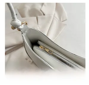 Close-up of smooth gold zipper closure and precise stitching on white leather bag