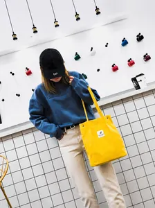 Primer plano de un bolso tote de pana amarillo brillante con una sudadera azul marino