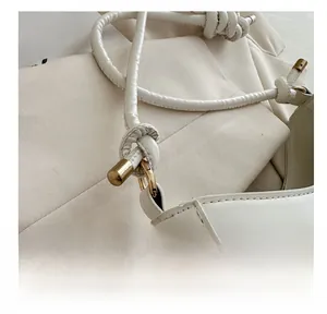 Close-up of white leather handbag with elegant knot strap and gold metal ring detail