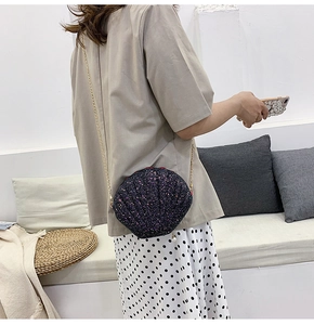 Detail of glitter shell crossbody bag with gold chain strap and pearl charm accessory
