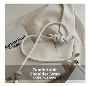 Close-up of comfortable white leather shoulder strap with gold hardware and knot detail