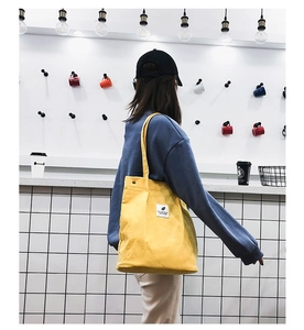 Détail d'un sac cabas en velours côtelé jaune avec étiquette en tissu sur le côté