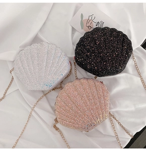 Three glittery shell-shaped crossbody bags in silver, black and pink with gold chains