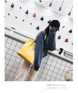 Détail du sac fourre-tout en velours côtelé jaune avec étiquette tissée et large bandoulière