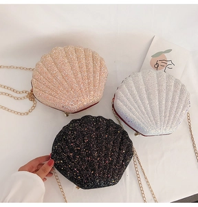 Detailed view of glitter shell-shaped cross-body bags in pink gold, silver, and black