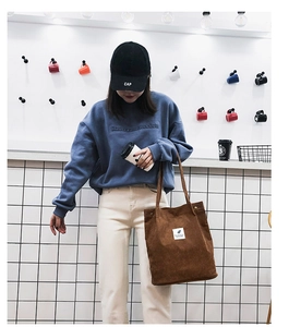 Détail d'un sac fourre-tout en velours côtelé marron avec patch blanc sur un mannequin