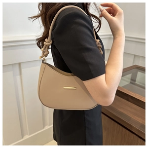 Detail of knotted shoulder strap and gold metal trim on beige crescent underarm bag
