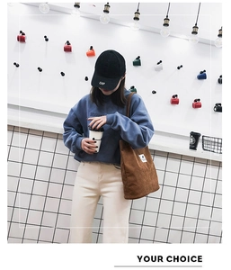 Détail d'un sac à bandoulière en velours côtelé marron avec un sweat bleu et pantalon
