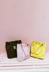 Vista detallada de bolsos tote de pana en marrón, rosa y amarillo con etiquetas tejidas