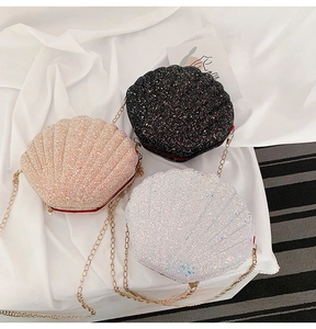 Detailed view of shimmering shell-shaped crossbody bags in black, pink, and white glitter finish
