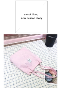 Détail du sac fourre-tout en velours rose avec bouton et étiquette blanche sur tissu