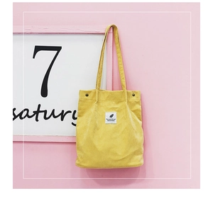 Gros plan d'un sac cabas en velours côtelé jaune avec texture côtelée et logo