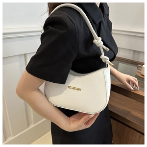 Detail of white half-moon shoulder bag featuring a knotted strap and gold metal clasp