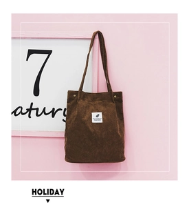 Détail d'un sac cabas en velours côtelé marron foncé montrant la texture et l'étiquette
