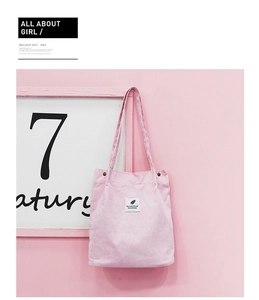 Gros plan du sac cabas en velours côtelé rose avec étiquette minimaliste et doubles bandoulières