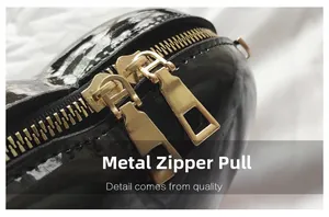 Detailaufnahme der doppelten goldenen Metallreißverschlüsse an einer schwarzen Herztasche