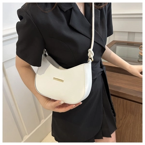 Detail of white half-moon hobo bag with gold metal trim and knotted shoulder strap