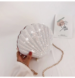 Detail of a shell-shaped silver sequin clutch with gold chain and pearl accent