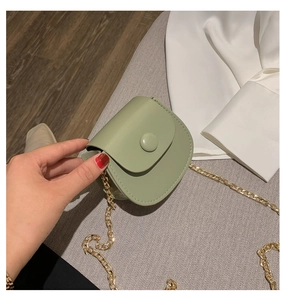 Detail van mintgroene mini zadeltas met leertextuur en een gouden ketting schouderriem