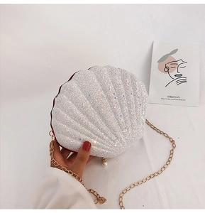 Detail of white shell-shaped evening bag with sequins, gold chain, and pearl pendant