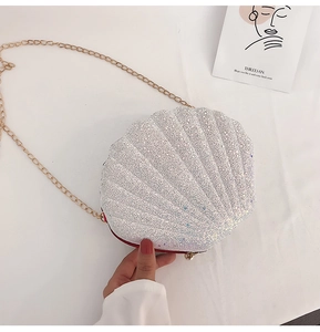 Detail of shell-shaped crossbody bag with silver glitter finish and gold chain