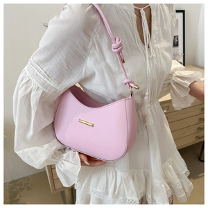 Detail of light pink crescent underarm bag with smooth leather finish and gold metal bar
