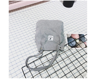 Détail du sac fourre-tout en velours côtelé gris clair avec étiquette sur fond à carreaux