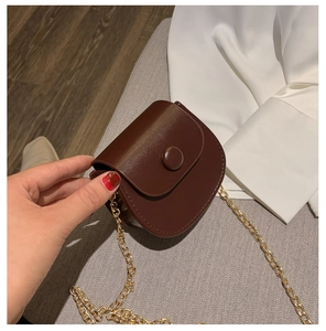 Detail van de donkerbruine mini zadeltas met gouden ketting en ronde gesp sluiting
