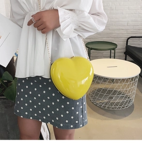 Detail einer leuchtend gelben herzförmigen Mini-Umhängetasche mit goldener Kette