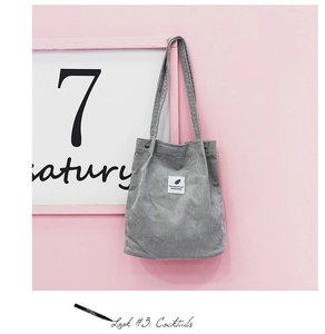 Détail d'un sac cabas en velours côtelé gris avec écusson feuille et boutons à pression