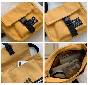 Detail view of yellow canvas messenger bag with black buckle and front fashion label