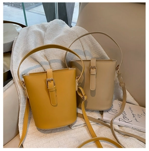 Detail view of stylish yellow and beige bucket bags on a soft textured linen background