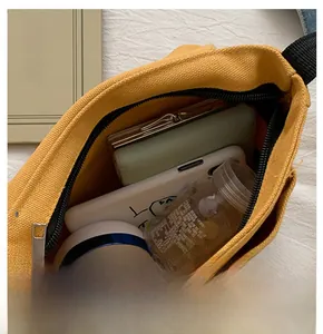 Internal capacity of mustard yellow canvas messenger bag showing phone and wallet