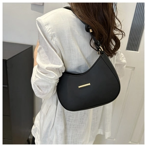 Detail of a black crescent underarm bag with gold metal buckle and matte leather finish