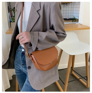 Lifestyle-Foto einer braunen Satteltasche aus Leder mit grauem Blazer und Jeans