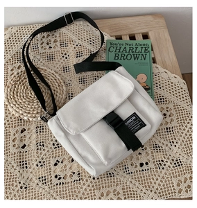 Detail of white canvas messenger bag with black buckle and adjustable shoulder strap